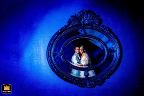 Dreamy Wedding Experience Captured at Kasteel de Haar in Utrecht with Soft Blue Lighting A couple stands in front of a round wall mirror at the Kasteel de Haar in Utrecht, Netherlands. Soft blue lighting creates a romantic atmosphere as they pose for photos on their wedding day.